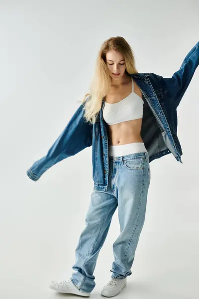 Une jeune femme virevolte gracieusement en denim surdimensionné, mettant en valeur le style et la confiance sans effort. — Photo de stock