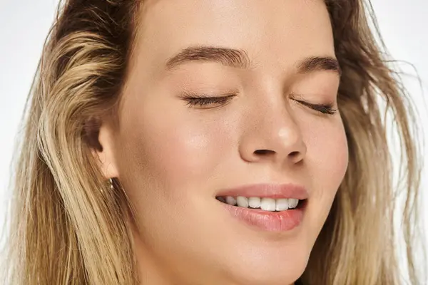 The young woman expresses joy and relaxation, her eyes closed, embracing a peaceful moment. — Stock Photo