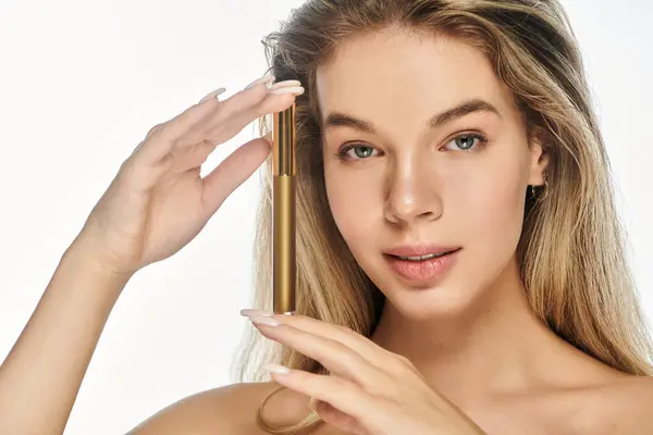 A smiling young woman showcases her skincare routine with a golden serum. — Stock Photo