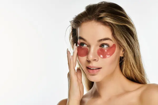 Uma jovem mulher bonita leva um momento para si mesma, aplicando manchas nos olhos para refrescar seu olhar. — Fotografia de Stock