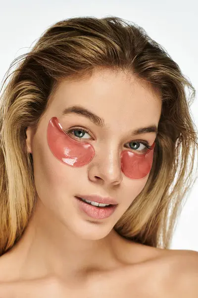 A beautiful young woman relaxes with soothing eye patches, enhancing her natural glow. — Stock Photo