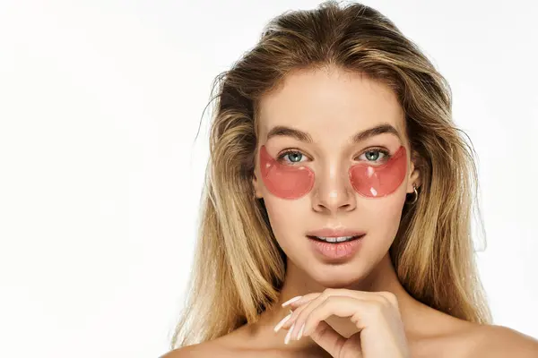 Una mujer joven disfruta de un momento relajante mientras aplica parches para los ojos para el rejuvenecimiento. — Stock Photo