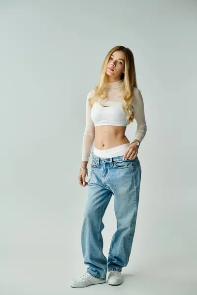 The beautiful young woman stands tall, showcasing her style and confidence in relaxed jeans. — Stock Photo