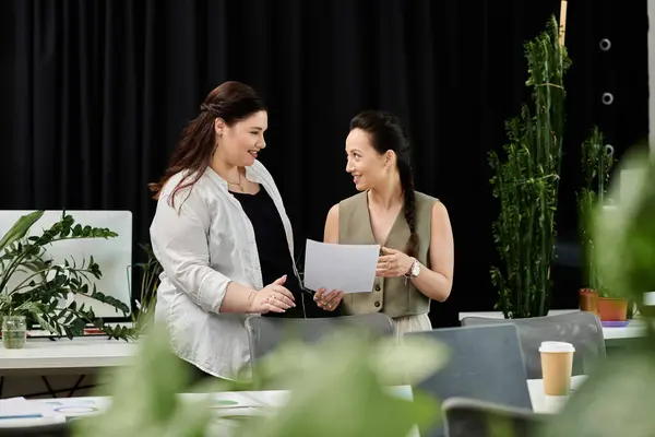 Two stylish professionals engage in a lively discussion while reviewing documents together. — Stock Photo