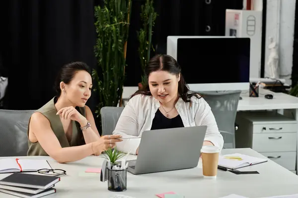 Zwei elegante Frauen diskutieren konzentriert, während sie digitale Inhalte in einem Büro prüfen. — Stockfoto