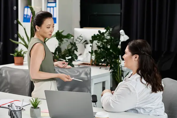 In a contemporary office, two professional women converse, sharing ideas and strategies. — Stock Photo