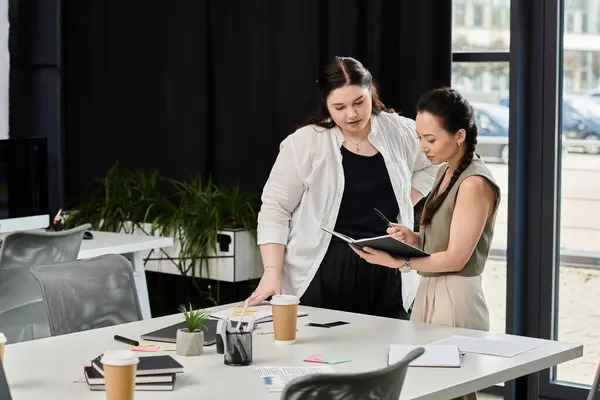 Zwei elegante Profis diskutieren Strategien, während sie Notizen in einem stilvollen Büroumfeld prüfen. — Stockfoto