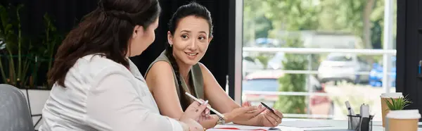 Dos mujeres profesionales están compartiendo ideas y discutiendo proyectos en un ambiente de oficina brillante. - foto de stock