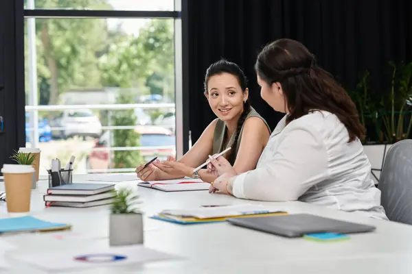 Two professionals engage in an inspiring discussion, sharing ideas and notes in a bright office. — Stock Photo