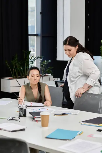 Two elegant business professionals discuss strategies while reviewing documents at a desk. — Stock Photo