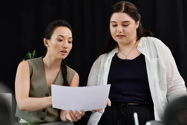 Two professionals discuss ideas over documents in a stylish corporate setting. — Stock Photo