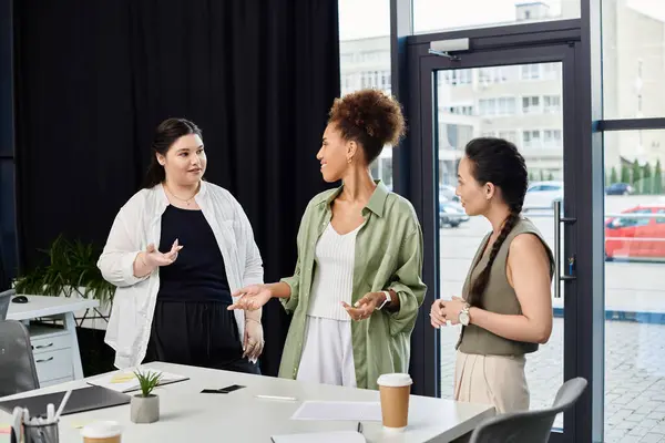 Drei geschäftstüchtige Frauen führen eine inspirierende Diskussion in einem modernen Büro. — Stockfoto