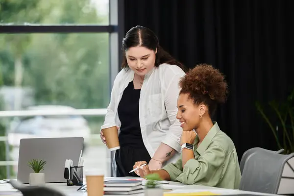 Two elegant women engage in productive discussion while reviewing documents in an office. — Stock Photo