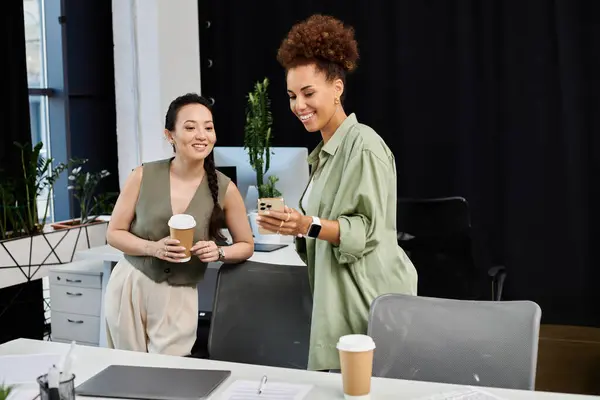 Two stylish businesswomen share ideas over coffee in a modern office. — Stock Photo