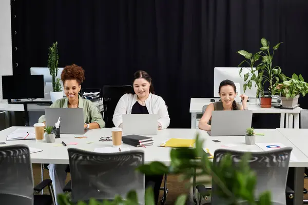 Three professional women are engaged in focused discussions and tasks in a bright office. — Stock Photo