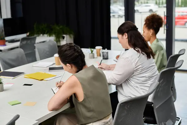 Tres profesionales participan en discusiones focalizadas y toma de notas en un espacio de trabajo contemporáneo. - foto de stock