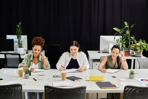 Three professional women focus on their tasks while discussing ideas in a sleek office space. — Stock Photo
