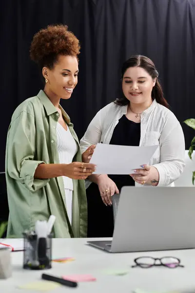 Two professional women discuss documents together in a stylish office environment. — Stock Photo