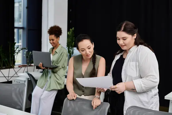 Three professionals engage in teamwork, discussing documents and sharing ideas in an office. — Stock Photo