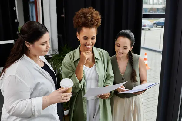 Three stylish businesswomen engage in productive discussion while reviewing documents together. — Stock Photo