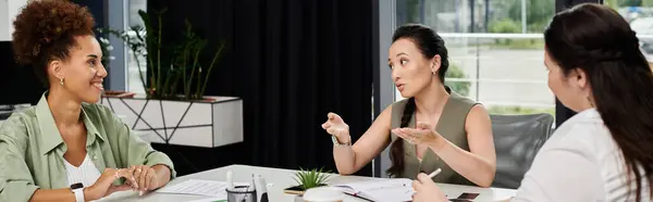Three confident businesswomen engage in a collaborative discussion in a sleek office environment. — Stock Photo