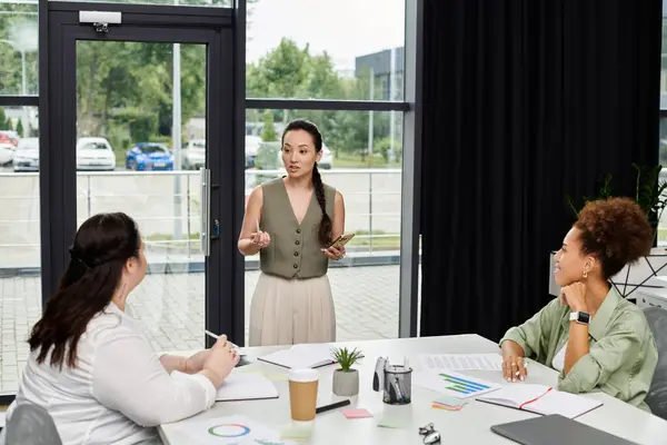 Three professional women collaborate and discuss ideas in a modern office environment. — Stock Photo