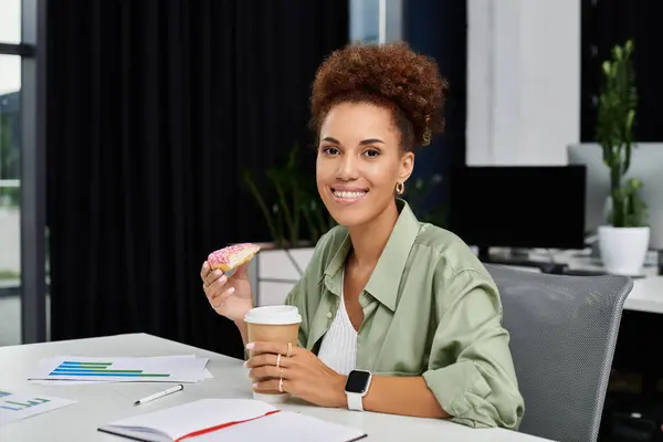 Un professionnel élégant savoure une friandise sucrée et du café, rayonnant de confiance dans son espace de travail. — Photo de stock