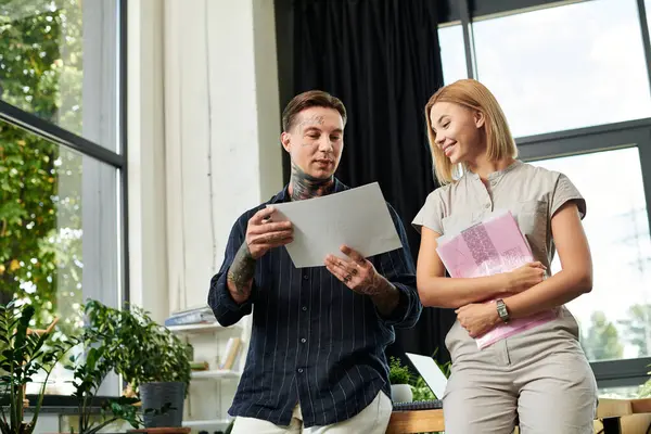 Dos jóvenes profesionales comparten ideas mientras revisan documentos en un entorno de oficina moderno. - foto de stock