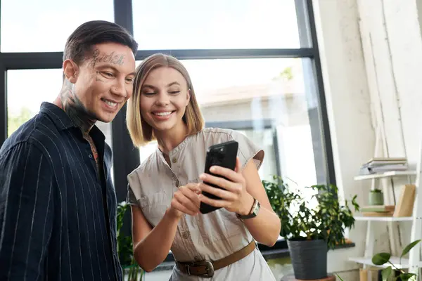 Dois jovens colegas de trabalho aproveitam seu tempo juntos enquanto revisam o trabalho em um smartphone. — Fotografia de Stock