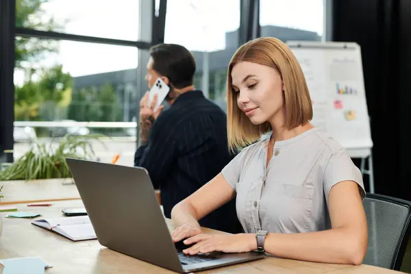 Dos jóvenes profesionales colaboran en un ambiente de oficina elegante, centrándose en su trabajo. - foto de stock