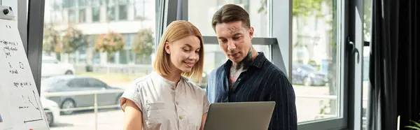 Two colleagues share ideas while working together at a laptop in a bright office environment. — Stock Photo
