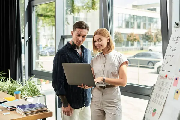 Two coworkers engage in discussion while reviewing a laptop, sharing ideas creatively. — Stock Photo