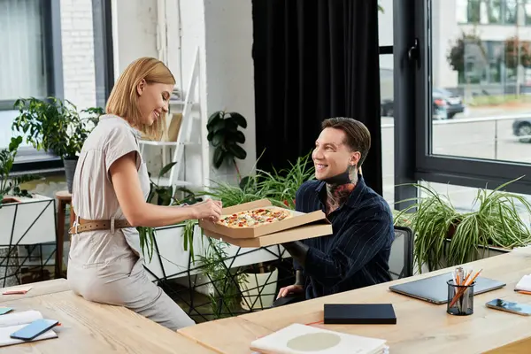 Two young professionals enjoy a delightful pizza break together in their vibrant office setting. — Stock Photo