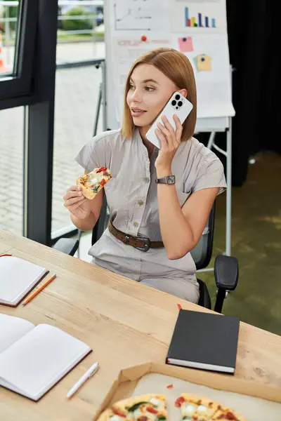 A young professional talks on the phone while having pizza. — Stock Photo