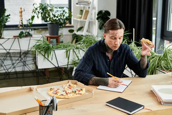A young employee takes notes while savoring pizza during a collaborative work session. — Stock Photo