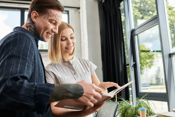 Zwei junge Berufstätige tauschen sich beim Durchsehen von Dokumenten im Büro begeistert aus. — Stockfoto