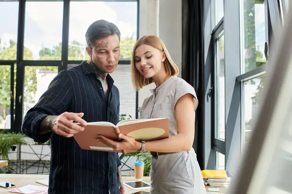 Two young professionals discuss ideas while reviewing material in a contemporary office environment. — Stock Photo