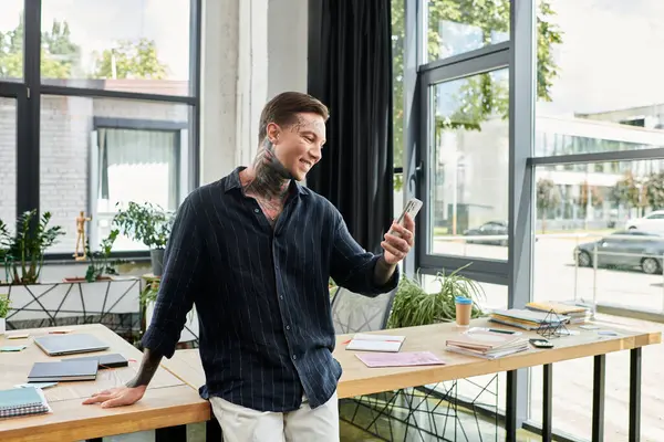 A young professional relaxes, smiling as he checks smartphone in a bright office. — Stock Photo