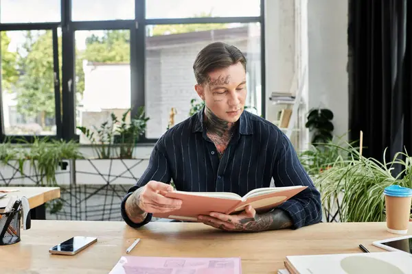 Ein Mitarbeiter studiert ein Buch intensiv, während er von einer lebendigen Büroatmosphäre umgeben ist. — Stockfoto