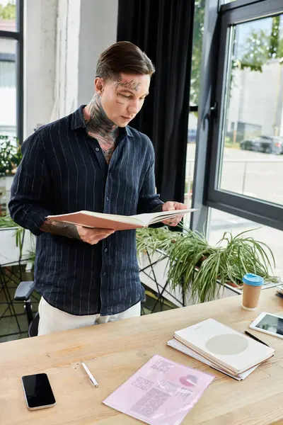 A young coworker reviews documents at a stylish office desk filled with stationery and greenery. — Stock Photo