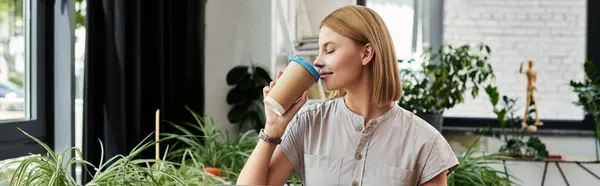 A young professional enjoys a beverage while surrounded by greenery and a modern workspace. — Stock Photo