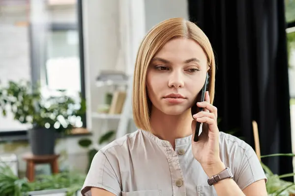 A young professional engages in a focused conversation on her phone, surrounded by greenery. — Stock Photo