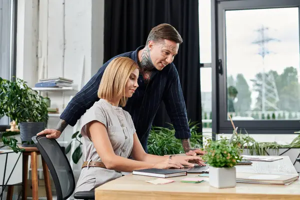 Two coworkers engage in a focused discussion while working at a desk surrounded by plants. — Stock Photo
