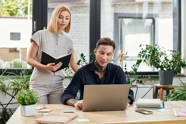 Two coworkers discuss ideas while working on a laptop in a bright office filled with greenery. — Stock Photo