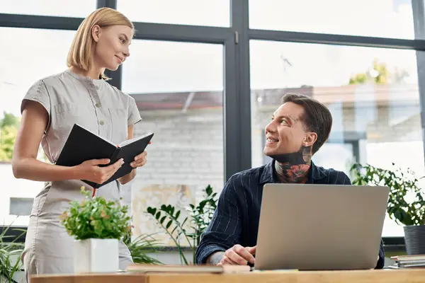 Two colleagues chat animatedly among vibrant plants in a bright workspace. — Stock Photo
