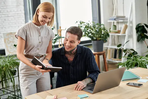 Two coworkers engage in a lively discussion while reviewing notes at a wooden desk. — Stock Photo