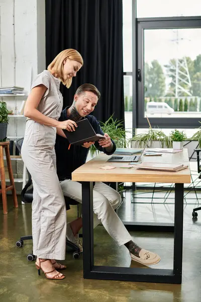 Two young professionals engage in lively discussion while reviewing work on a tablet. — Stock Photo