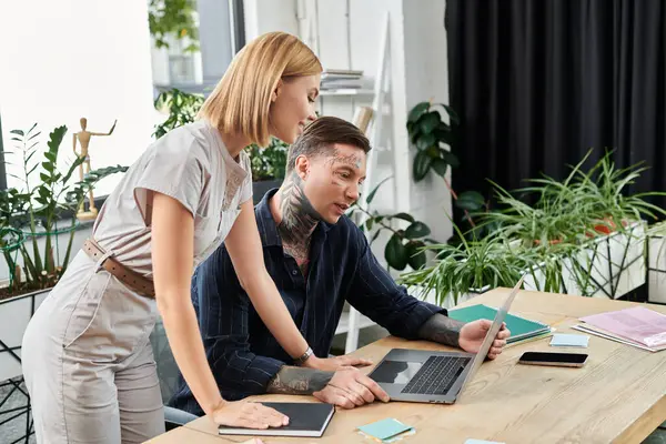 Two young professionals engage in a team discussion at their workspace with plants around them. — Stock Photo