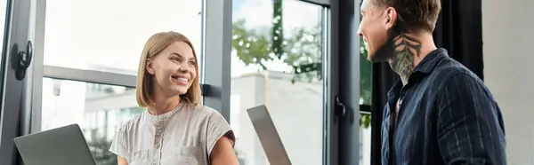 Two young colleagues share ideas and smiles in a modern office environment. — Stock Photo
