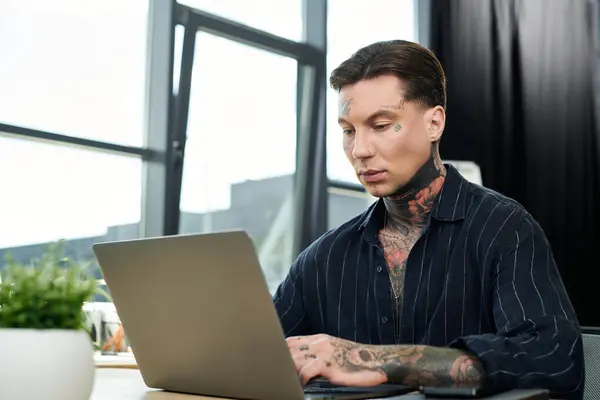 Um homem focado trabalha intensamente em um laptop em um ambiente de escritório elegante. — Fotografia de Stock
